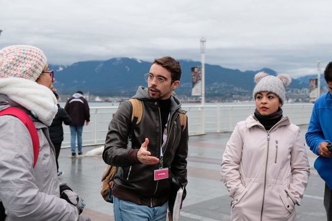 Tour guide of GuruWalk explains something to travelers on a free walking tour in Vancouver.